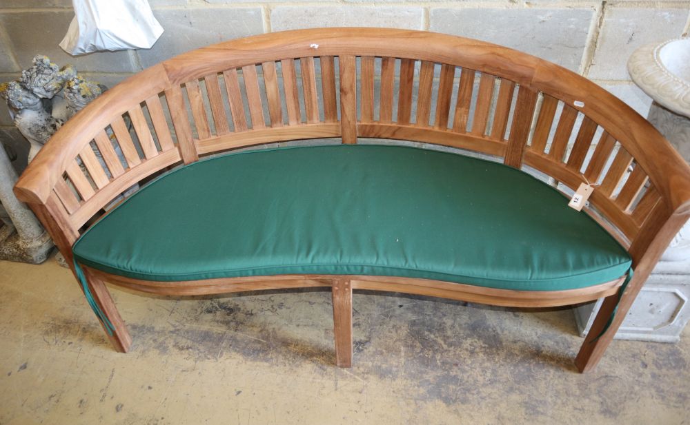 A teak garden banana bench with cushion seat, W.160cm, D.54cm, H.85cm